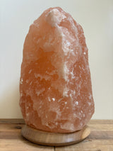 Himalaya zoutlamp 12-15kg, middelgroot  formaat met warme, natuurlijke gloed, op stevige houten voet.