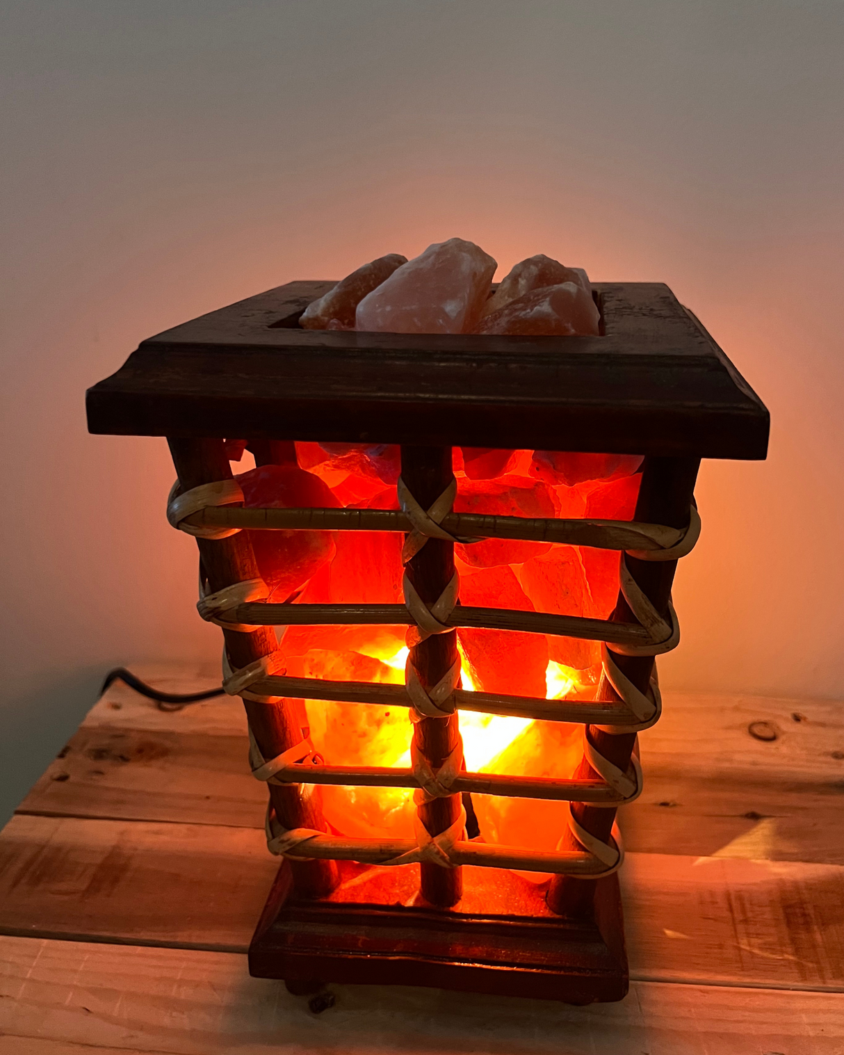 Trapeze mand van riet en hout gevuld met zoutsteenbrokken, inclusief lamp en kabel voor warme, sfeervolle verlichting.