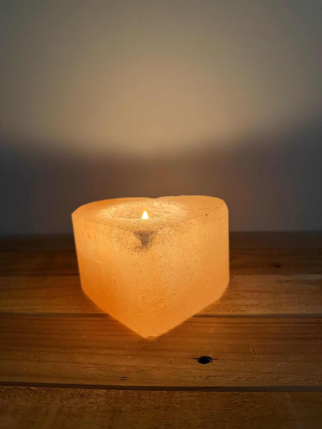 Handgemaakte hartvormige waxinelichthouder van natuurlijke zoutsteen met warme oranje gloed