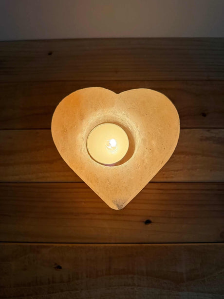 Handgemaakte hartvormige waxinelichthouder van natuurlijke zoutsteen met warm oranje gloed