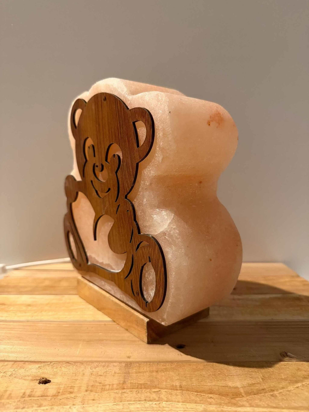 Handgemaakte Himalaya zoutlamp in de vorm van een beer met warm licht en houten voet.