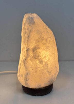 Brandende Himalaya zoutlamp grijs 2-3 kg met warme gloed op houten voet
