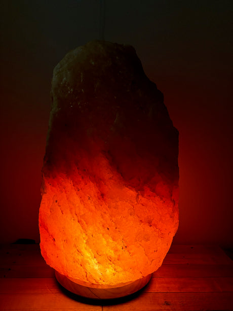 Lichte Himalaya zoutlamp 70–80 kg met warme gloed op robuuste houten voet